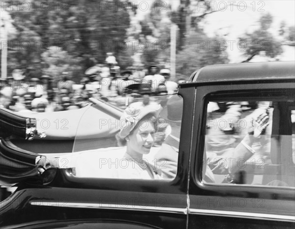 Princess Elizabeth drives past. Princess Elizabeth and the Duke of Edinburgh wave to crowds of well-wishers as they drive past in an open-topped car on their way to City Hall. Nairobi, Kenya, February 1952. Nairobi, Nairobi Area, Kenya, Eastern Africa, Africa.