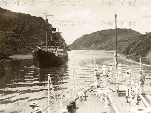 Culebra Cut section of the Panama Canal. HMS Dauntless of the Royal Navy's South American Division passes Santa Elisa of the Panama Mail Steamship Company on the Culebra Cut section of the Panama Canal. Panama, circa 1931. Panama, Central America, North America .