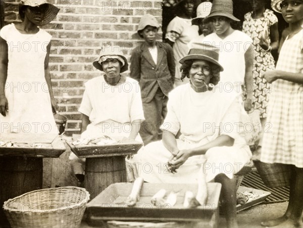 Fish stall in St Lucia. A female trader sits smoking a pipe at her street stall, where she sells fish displayed on a tray. St Lucia, circa 1931., St Lucia, St Lucia, Caribbean, North America .