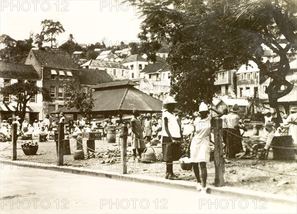 Marketplace in St George. View of a bustling marketplace in St George, where traders set up stalls in a square bordered by tall, commercial buildings. St George, Grenada, circa 1931. St George's, St George (Grenada), Grenada, Caribbean, North America .
