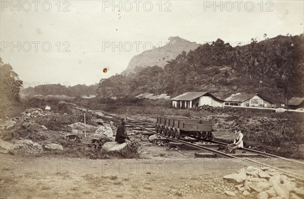 A Ceylon Government Railway track. Two men sit beside an empty rail cart on tracks belonging to the Ceylon Government Railway. Ceylon (Sri Lanka), circa 1865. Sri Lanka, Southern Asia, Asia.