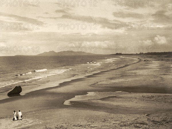 Malabar Coast and Mount Deli. Two tiny figures walk along a vast sandy beach on the Malabar Coast with Mount Deli in the distance. This was the landing place of Portuguese explorer Vasco da Gama (c.1469-1524), the first person to sail directly from Europe to India. Malabar District (Kerala), India, circa 1936., Kerala, India, Southern Asia, Asia.