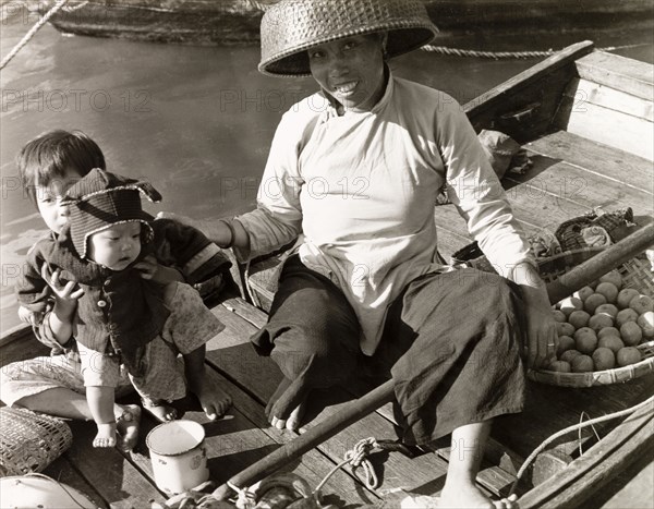 Selling fruit from a sampan. A woman with two young children sells fruit from a sampan in Aberdeen Harbour. Hong Kong, China, 1963. Aberdeen, Hong Kong, China, People's Republic of, Eastern Asia, Asia.