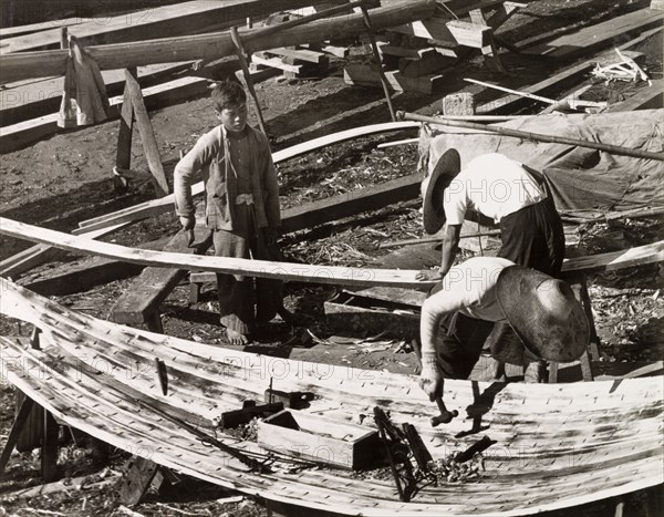 Constructing a sampan. Two men build a sampan at a boatyard in Aberdeen Harbour, whilst a third watches the work in progress. Aberdeen, Hong Kong, China, 1963. Aberdeen, Hong Kong, China, People's Republic of, Eastern Asia, Asia.