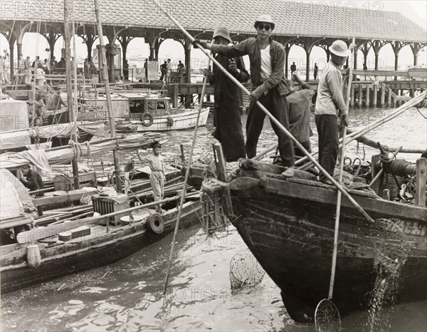 Fishing in a Hong Kong harbour. Fishermen stand at the bow of their sampan, dipping long-handled fishing nets into the waters of a Hong Kong harbour. Hong Kong, China, 1963., Hong Kong, China, People's Republic of, Eastern Asia, Asia.
