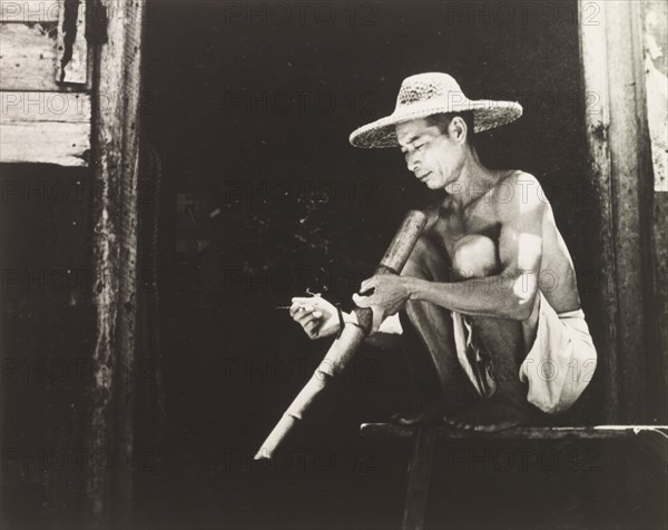 Smoking a bamboo pipe. A Chinese worker enjoys his bamboo pipe during a smoking break. Hong Kong, China, 1963. Hong Kong, Hong Kong, China, People's Republic of, Eastern Asia, Asia.