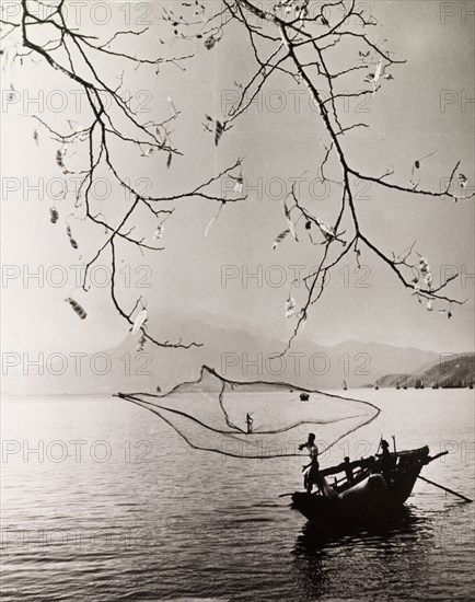 Fishing in a Hong Kong bay. A fisherman casts his net into the tranquil waters of a Hong Kong bay. Hong Kong, China, 1963., Hong Kong, China, People's Republic of, Eastern Asia, Asia.