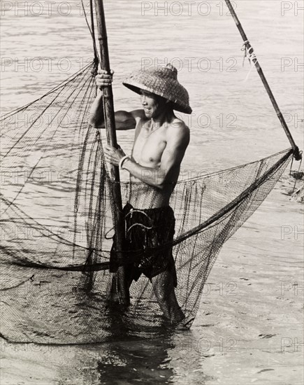 Fishing in shallow waters. A fisherman trawls his net in the shallow waters of a Hong Kong bay. Hong Kong, China, 1963., Hong Kong, China, People's Republic of, Eastern Asia, Asia.