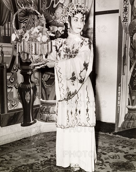 Portrait of a Chinese actress. An actress from a Chinese opera poses with a basket of flowers, wearing an embroidered costume, theatrical makeup and a decorative headpiece. Hong Kong, China, 1963., Hong Kong, China, People's Republic of, Eastern Asia, Asia.
