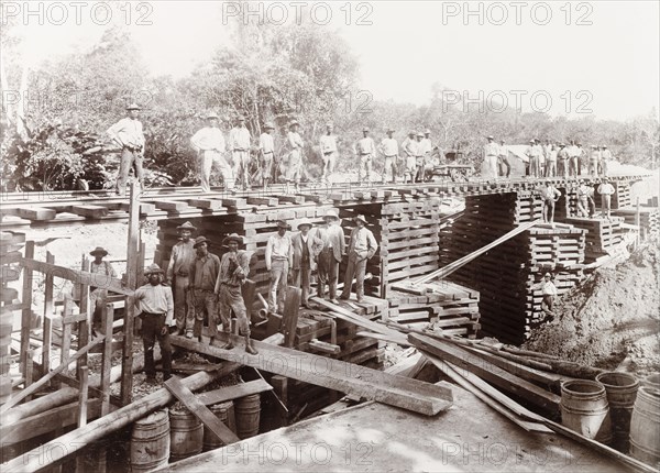 Temporary bridge over Caparo River, Trinidad. Trinidad Government Railway workers pose for a photograph during the construction of a temporary bridge over Caparo River, built as part of an extended railway line through Caparo Valley to Rio Claro. Trinidad, circa 1912., Trinidad and Tobago, Trinidad and Tobago, Caribbean, North America .