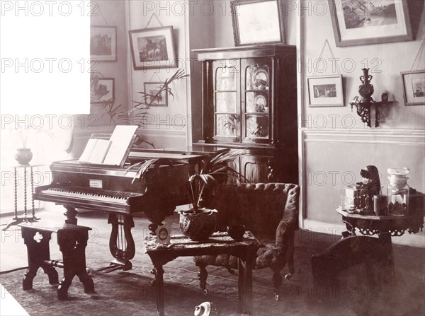 A Victorian drawing room. A grand piano stands in the corner of the Victorian-style drawing room of the flat above the British-owned 'James Murray and Co.' family business located at 12 Government Place. Calcutta (Kolkata), India, circa 1900. Kolkata, West Bengal, India, Southern Asia, Asia.