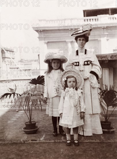 An Edwardian family. Portrait of Minnie Murray, elegantly dressed in Edwardian-style, posing with her two daughters, Jessie and Enid, on a rooftop garden in Calcutta. Calcutta (Kolkata), India, 1906. Kolkata, West Bengal, India, Southern Asia, Asia.