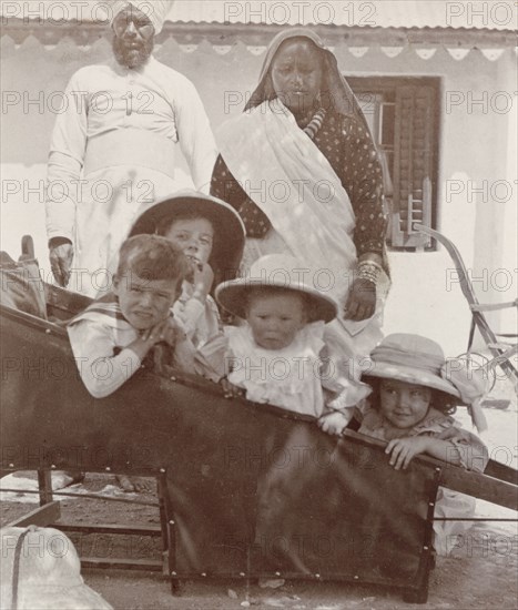 British children in a sedan chair. An Indian servant and ayah (nursemaid) watch over four young British children as they sit in a sedan chair. Mussoorie, India, circa 1907. Mussoorie, Uttaranchal, India, Southern Asia, Asia.
