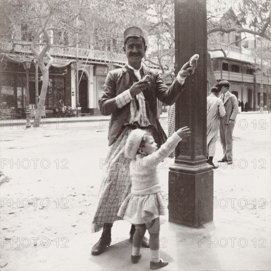 Gully gully man' performing a trick. An Egyptian 'gully gully man' (travelling magician) performs a sleight of hand trick involving live chicks on young passer-by, Enid Murray. Suez, Egypt, 1909. Suez, Suez, Egypt, Northern Africa, Africa.