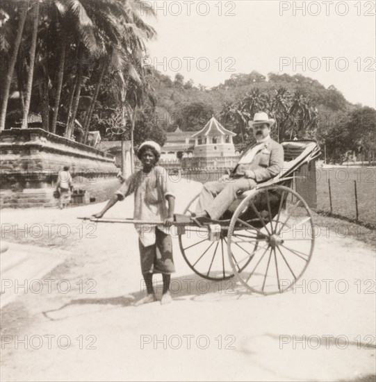James Murray travelling by rickshaw. James Murray takes a ride in a rickshaw through the streets of Colombo. Colombo, Ceylon (Sri Lanka), circa 1919. Colombo, West (Sri Lanka), Sri Lanka, Southern Asia, Asia.
