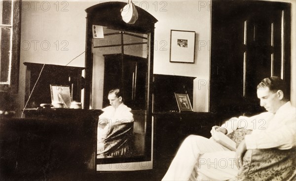 Feeling homesick in Calcutta. James Murray sits reading in his bedroom in Calcutta, homesick for his family and friends back in England. Calcutta (Kolkata), India, December 1930. Kolkata, West Bengal, India, Southern Asia, Asia.