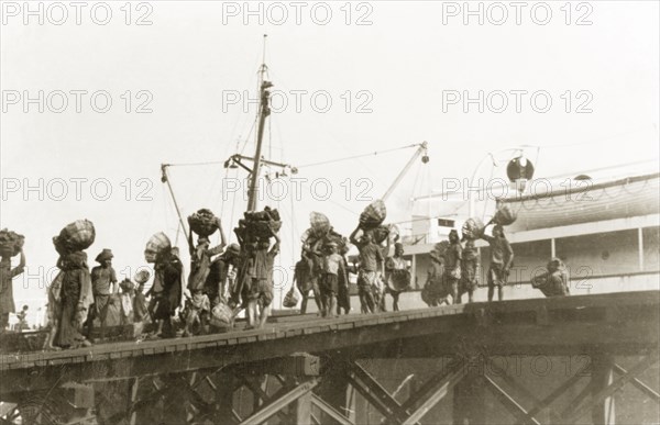 Coaling, the old fashioned way'. Indian porters refuel a ship with coal at Calcutta docks. Calcutta (Kolkata), India, 1931. Kolkata, West Bengal, India, Southern Asia, Asia.