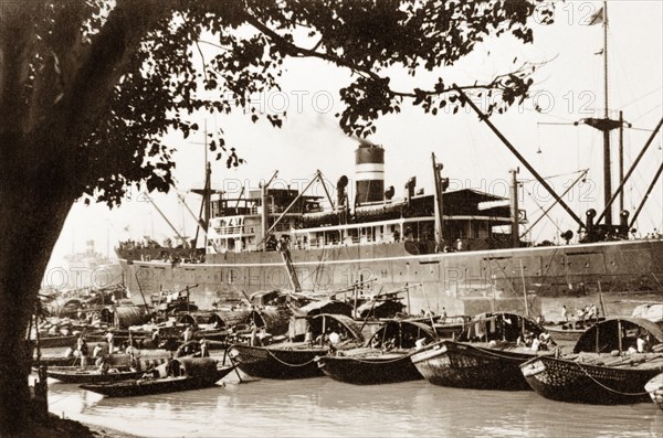 Moorings on the Hooghly River. Sampans moored on the Hooghly River are dwarfed by a European steamship at Calcutta docks. Calcutta (Kolkata), India, 1931. Kolkata, West Bengal, India, Southern Asia, Asia.