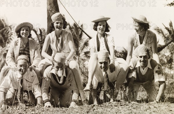 Fun and games during a picnic, Calcutta. Portrait of a group of British friends joking around during a picnic at Diamond Harbour. The men wear matching kufis (caps) and crawl on their hands and knees, while their female companions ride on their backs. Calcutta (Kolkata), India, 1933. Kolkata, West Bengal, India, Southern Asia, Asia.