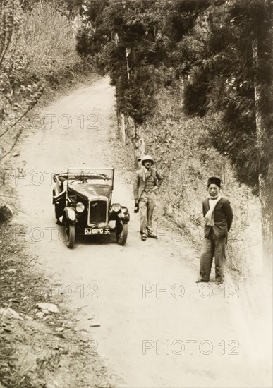Posing by an Austin 7, Assam. Dr Reid Tweedie, accompanied by his head servant, poses by his Austin 7 car on a rural road in the Dooars, a flood plain region in the foothills of the eastern Himalayas. Assam, India, April 1935., Assam, India, Southern Asia, Asia.