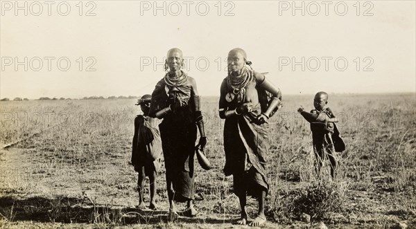 Maasai women and children collecting wood. Two Maasai women and two young children carry bundles of firewood and gourds of water in the Sanya Plains. Kilimanjaro, Tanganyika Territory (Tanzania), circa 1930., Kilimanjaro, Tanzania, Eastern Africa, Africa.
