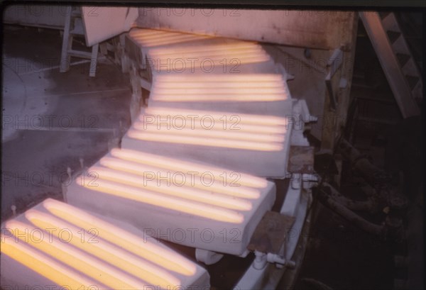 Molten copper at Nkana-Kitwe. Moulds containing molten copper rotate on a conveyor belt at a copper factory. Nkana-Kitwe, Northern Rhodesia (Zambia), circa 1962. Nkana-Kitwe, Copperbelt, Zambia, Southern Africa, Africa.