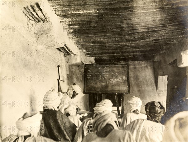 Adult students in a classroom, Kano. Adult students take notes from the blackboard during a lesson held inside a mud-walled classroom. Kano, Nigeria, circa 1914. Kano, Kano, Nigeria, Western Africa, Africa.
