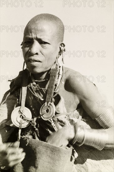 Kikuyu woman wearing traditional jewellery. Portrait of a Kikuyu woman wearing traditional jewellery including copper armbands and elaborate ear decorations. Kenya, circa 1932. Nyeri, Central (Kenya), Kenya, Eastern Africa, Africa.