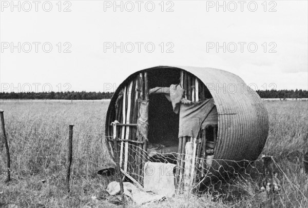 A shepherd's hut on the Laikipia plains. A shepherd's hut, made from a cylinder of corrugated iron and fortified with tree branches, stands in a field on the Laikipia plains. Central Kenya, circa 1935., Central (Kenya), Kenya, Eastern Africa, Africa.
