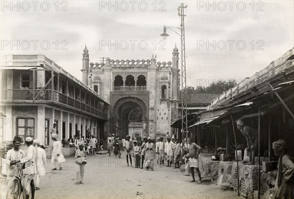 Gateway on city street, Jaora. View along a bustling city street to a large, Islamic-style arched gateway. Jaora State, Malwa Agency (Madhya Pradesh), India, 3 August 1928., Madhya Pradesh, India, Southern Asia, Asia.