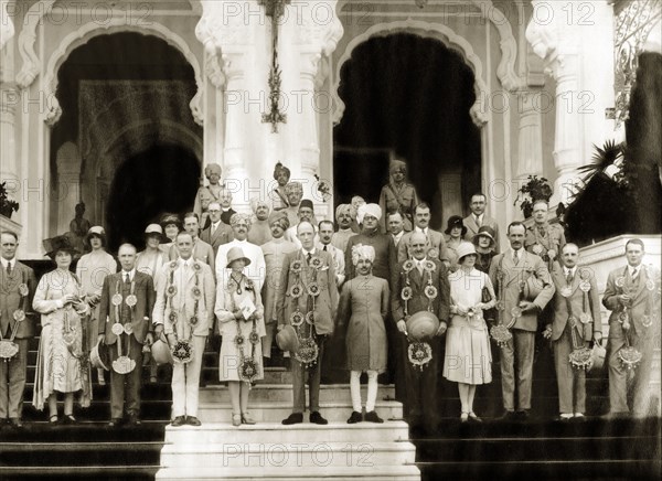 Group portrait of Lord Irwin and Maharaja of Ratlam. Lord Irwin, Viceroy of India, and his entourage, all adorned with decorative beadwork garlands, pose for a group portrait with Sajjan Singh Bahadur, Maharaja of Ratlam, on his palace steps. Ratlam State, Malwa Agency (Madhya Pradesh), India, 3 August 1928., Madhya Pradesh, India, Southern Asia, Asia.