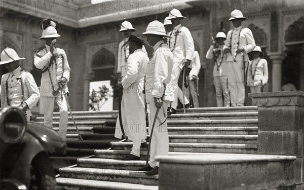 Viceregal entourage at Daly College. Officers of Lord Irwin's viceregal entourage, all in full dress uniform, wait on the steps of Daly College for the Viceroy to complete a guided tour of the college. Indore, Indore State (Madhya Pradesh), India, 31 July 1928. Indore, Madhya Pradesh, India, Southern Asia, Asia.