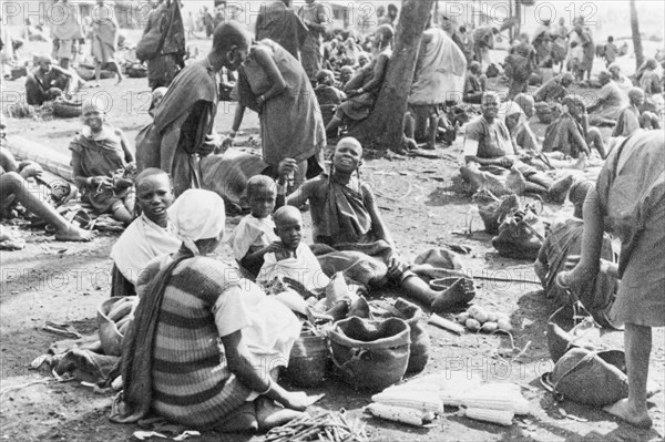 A homegrown vegetable market . Women and children sit together in groups at an outdoor market, selling small amounts of homegrown fruit and vegetables. Kenya, circa 1935., Kenya, Eastern Africa, Africa.