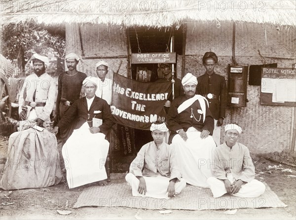Post Office staff, Edakkara. Group portrait of the Indian staff and officials of the Edakkara camp Post Office, who pose with a banner welcoming His Excellency the Governor of Madras. Sir Arthur Lawley visited Edakkara to attend a hunting expedition in the Nilgiri Hills with the Elaya Rajah (heir apparent) of Nilambur. Edakkara, Malabar District (Kerala), India, March 1908., Kerala, India, Southern Asia, Asia.