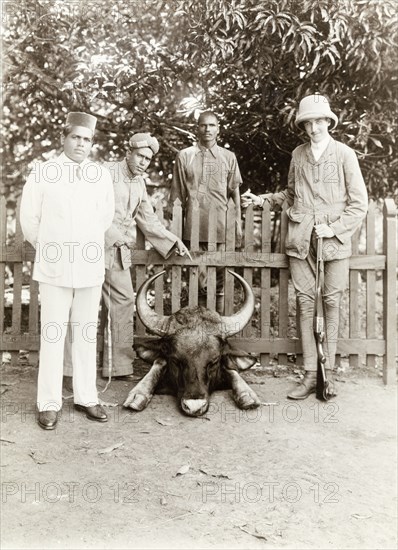 Gordon Leatham with hunting trophy, India. The Elaya Rajah (heir apparent) of Nilambur and Gordon Leatham, accompanied by two 'shikaris' (professional hunters), pose proudly beside the head of a Gaur (Bos gaurus), shot by Mr Leatham during a hunting expedition in the Nilgiri hills. Edakkara, Malabar District (Kerala), India, March 1908., Kerala, India, Southern Asia, Asia.