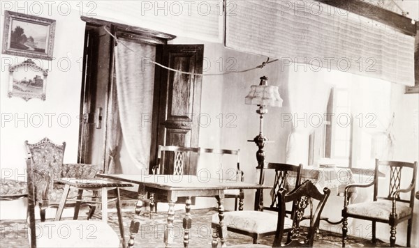 Governor's drawing Room at Edakkara lodge. Interior shot of the drawing room in the bungalow at Edakkara hunting lodge, taken during the stay of Sir Arthur Lawley, the Governor of Madras. Above the table hangs a 'pukka', a length of material swished by a servant to keep the guests cool. Edakkara, Malabar District (Kerala), India, March 1908., Kerala, India, Southern Asia, Asia.