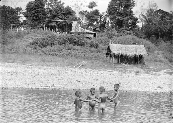 Children playing in water, Burma. Four young Burmese children stand in a circle holding hands as they play a game in the shallow water of a river. Burma (Myanmar), circa 1890. Burma (Myanmar), South East Asia, Asia.