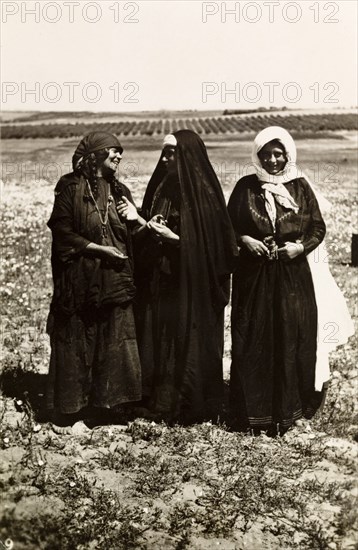 Palestinian bedouin women. Portrait of three Palestinian bedouin women standing in open countryside, two of whom are engaged in animated conversation. British Mandate of Palestine (Middle East), circa 1942., Middle East, Asia.