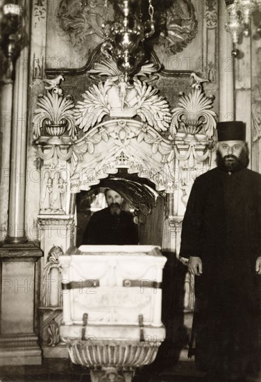 The Tomb of Christ, Jerusalem. Two monks pose beside the Tomb of Christ in the Church of the Holy Sepulchre. Jerusalem, British Mandate of Palestine (Israel), circa 1942. Jerusalem, Jerusalem, Israel, Middle East, Asia.