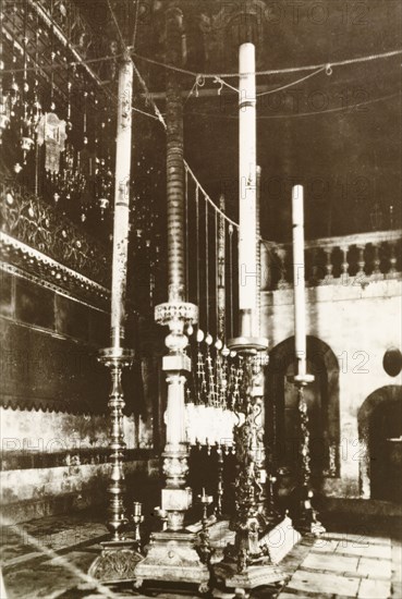 Candles in Church of the Holy Sepulchre. View of the tall, ornate candles at a shrine in the Church of the Holy Sepulchre, a Christian church believed to be built over Calvary (Golgotha), the site on which Jesus was crucified. Jerusalem, British Mandate of Palestine (Israel), circa 1942. Jerusalem, Jerusalem, Israel, Middle East, Asia.
