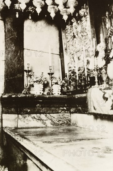 Interior of Tomb of Christ, Jerusalem. Candles line the interior of the Tomb of Christ in the Church of the Holy Sepulchre, a Christian church believed to be built over Calvary (Golgotha), the hill on which Jesus was crucified. Jerusalem, British Mandate of Palestine (Israel), circa 1942. Jerusalem, Jerusalem, Israel, Middle East, Asia.