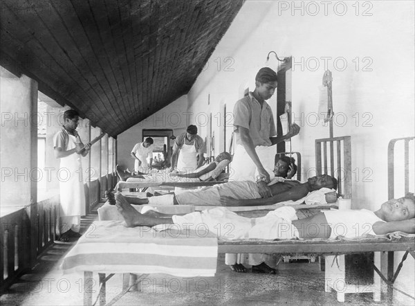 Male ward of a mission hospital, India. Indian medical officers tend to bedridden patients on the male ward of a hospital run by the London Missionary Society. India, circa 1930. India, Southern Asia, Asia.