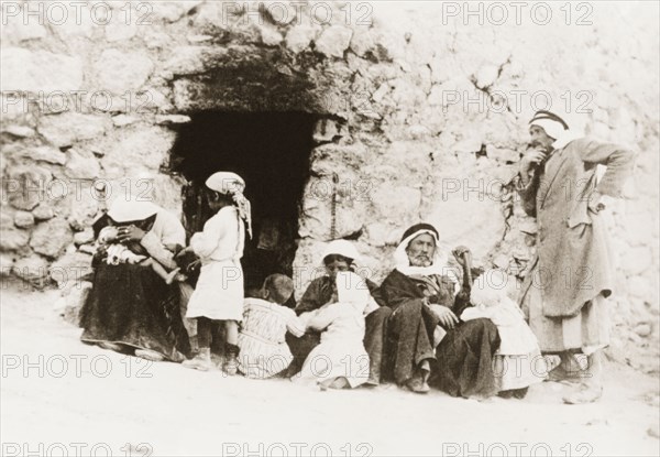 An Arab family, Palestine. An Arab family sit at the entrance of a stone dwelling. British Mandate of Palestine (Middle East), circa 1938., Middle East, Asia.