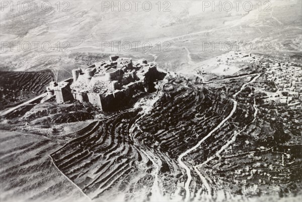 Castle overlooking a Palestinian settlement. An ancient castle with terraced ramparts sits atop a mountain, overlooking a Palestinian settlement in the valley below. British Mandate of Palestine (Middle East), circa 1938., Middle East, Asia.