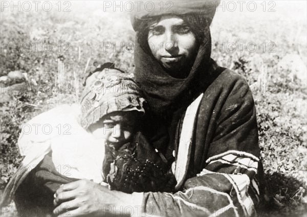 Bedouin mother and child, Palestine. A young bedouin mother cuddles her baby on her lap. British Mandate of Palestine (Middle East), circa 1938., Middle East, Asia.