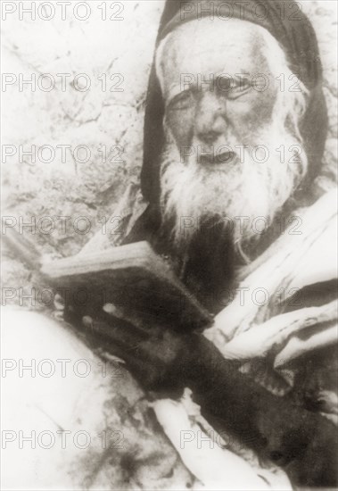 Portrait of an elderly Arab man. Portrait of an elderly Arab man reading from a book. British Mandate of Palestine (Middle East), circa 1938., Middle East, Asia.