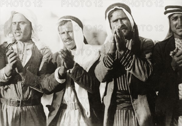 Pilgrims at a Nebi Musa procession. Four Arab men clap their hands together as they take part in a Nebi Musa procession: an annual pilgrimage made by Palestinian Muslims to Nebi Musa near Jericho, the supposed burial place of Moses. Ramallah, British Mandate of Palestine (West Bank, Middle East), circa 1938. Ramallah, West Bank, West Bank (Palestine), Middle East, Asia.