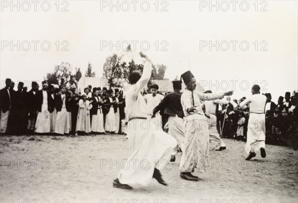 Dancing at an Arab wedding, Palestine. Several men perform a traditional dance at an Arab wedding, encircled by a crowd of onlookers. British Mandate of Palestine (Middle East), circa 1938., Middle East, Asia.