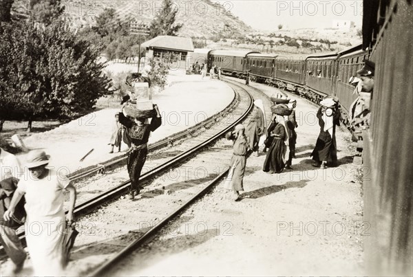 On the Jerusalem railway line. Passengers balance baskets on their heads as they disembark from a stationary train on the Jerusalem railway line. British Mandate of Palestine (Israel), circa 1938. Israel, Middle East, Asia.