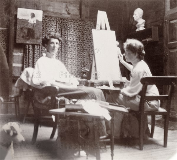 Minnie Murray poses for a painted portrait. Minnie Murray sits in a chair in an art studio, posing for a female friend who paints her portrait on a canvas and easel. Mussoorie, India, 1907. Mussoorie, Uttaranchal, India, Southern Asia, Asia.